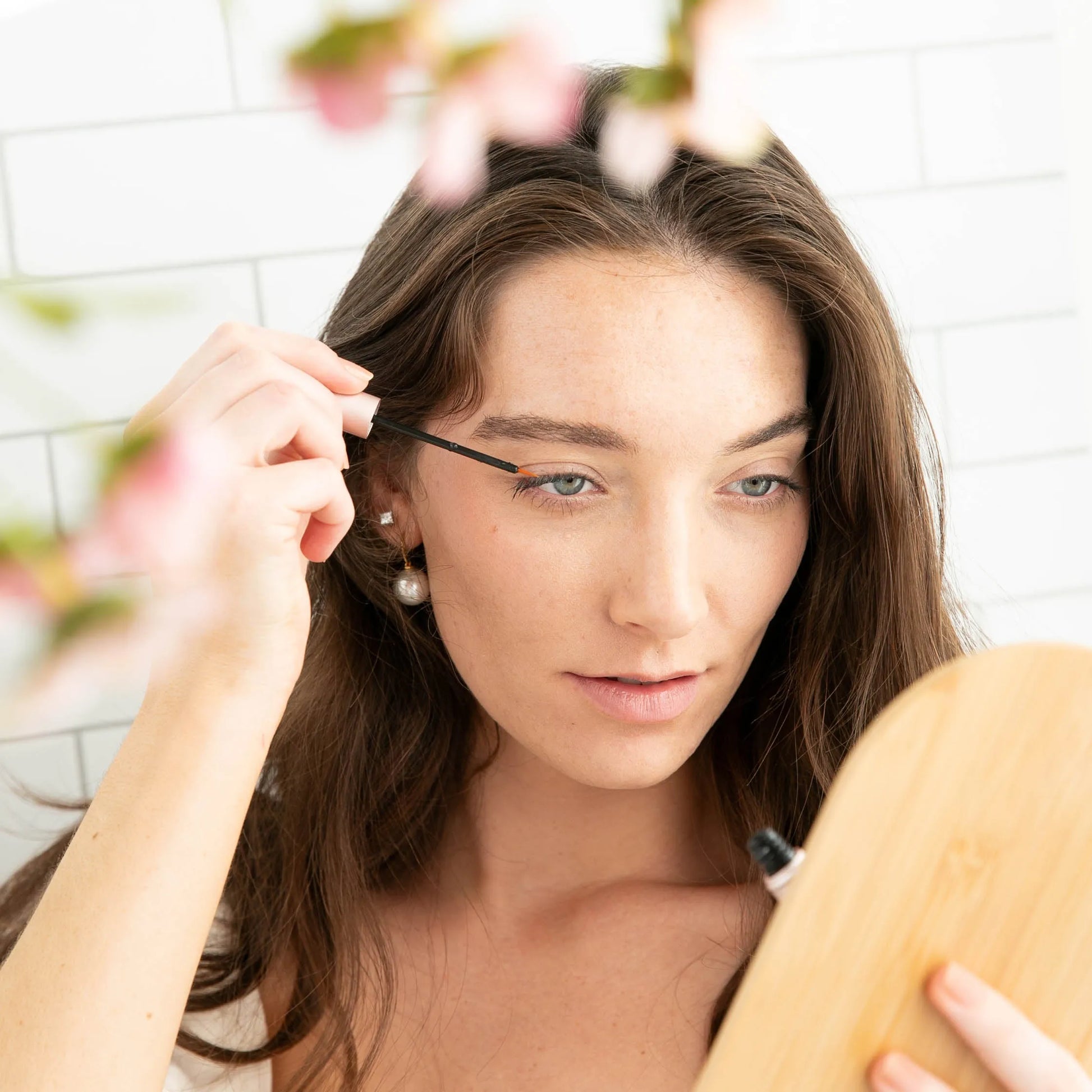 Woman applying MiyLash Mini Lash and Brow Growth Serum with a precise brush, perfect for travel-friendly eyelash care.